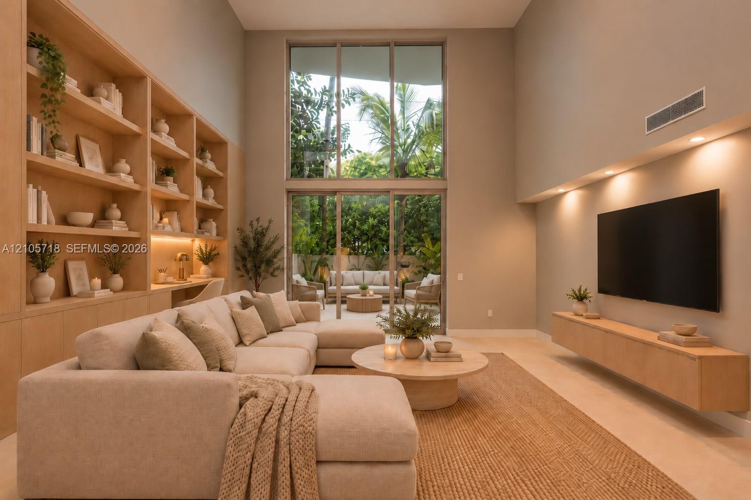 Double-height ceiling featuring expansive floor-to-ceiling windows, custom built-in light-tone wood shelving with integrated task lighting, and a wall