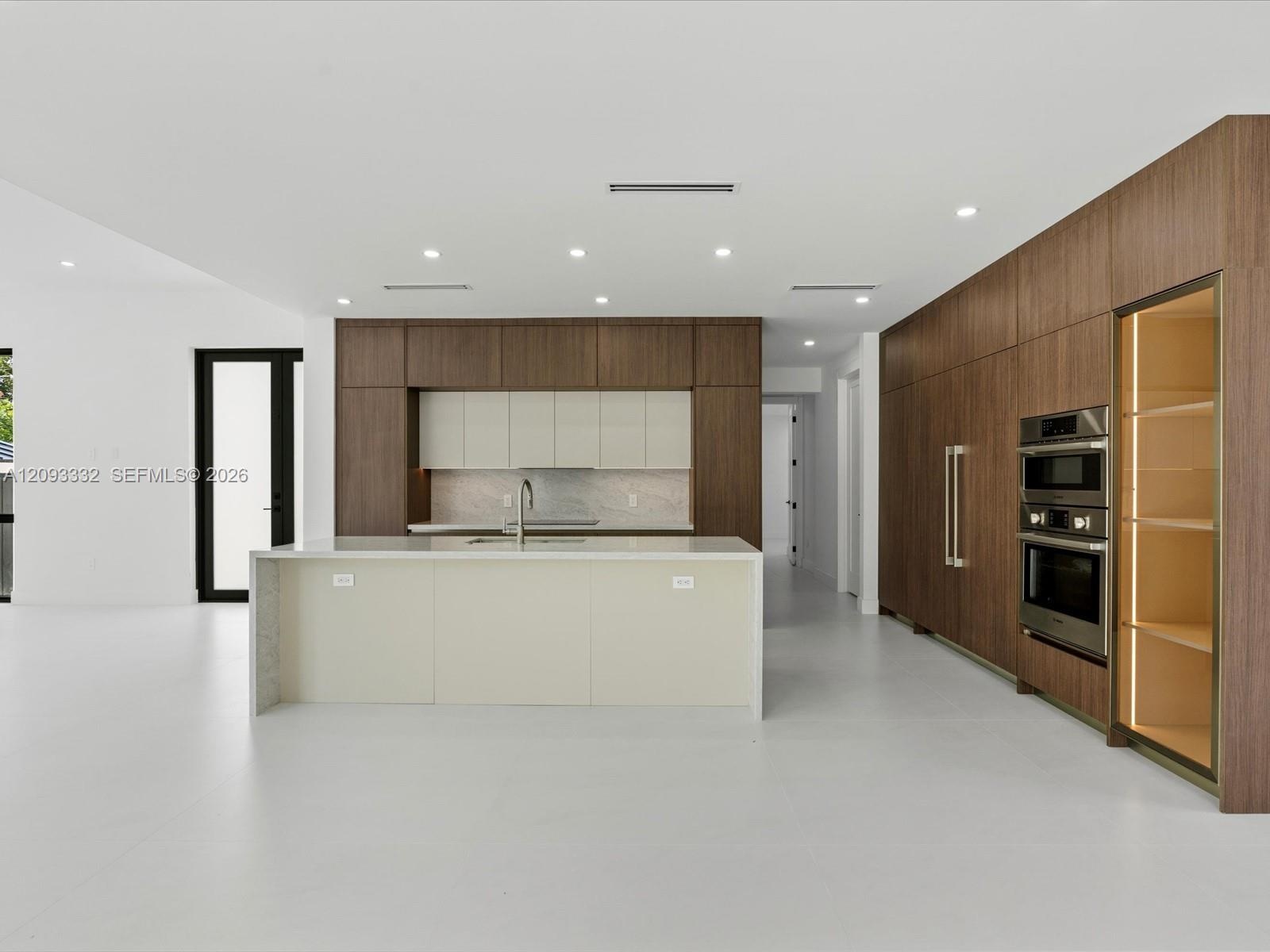 Kitchen featuring wood-finish cabinetry, central island with stone-surface countertop, built-in double wall oven, integrated refrigerator paneling, an