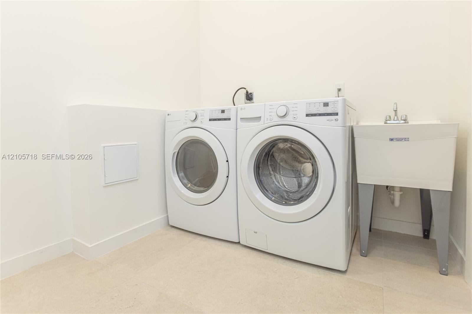 Utility area featuring a deep-basin laundry sink with a dual-handle faucet and dedicated washer and dryer connections