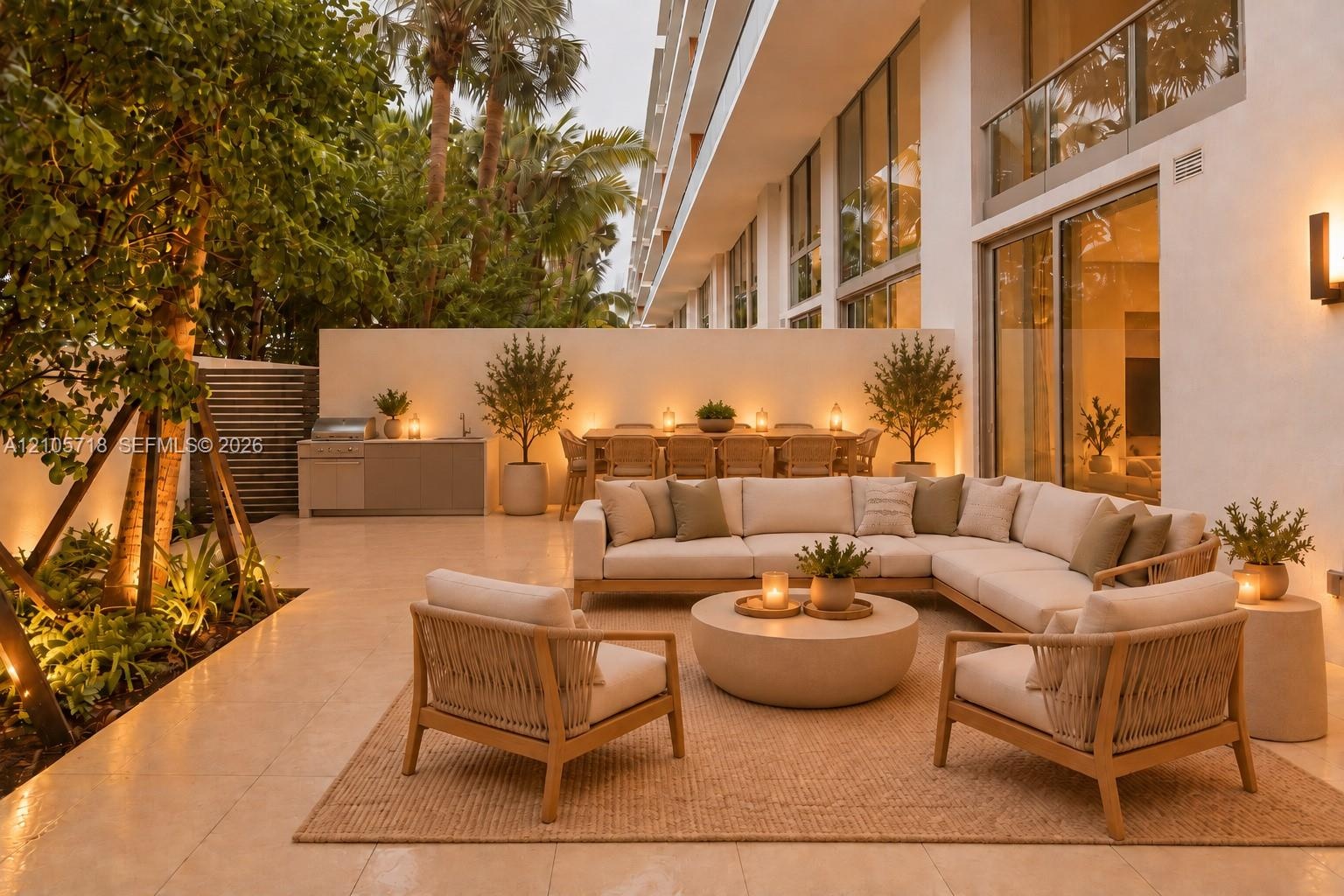 Private patio featuring stone tile flooring, a built-in outdoor kitchen with stainless steel grill, tall privacy walls, and full-height glass sliding 