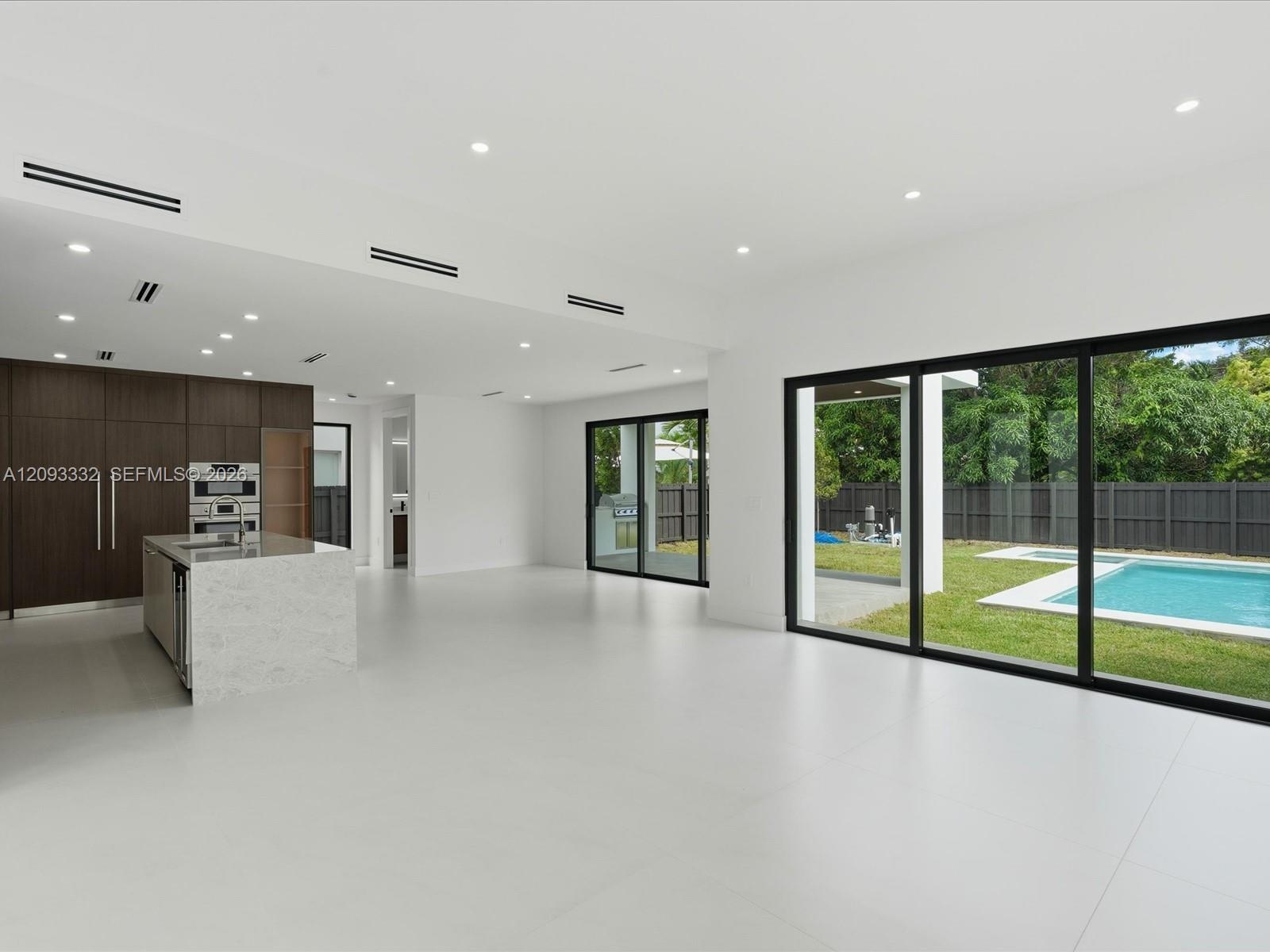 Open-concept interior featuring large-format tile flooring, recessed lighting, and expansive black-framed sliding glass doors