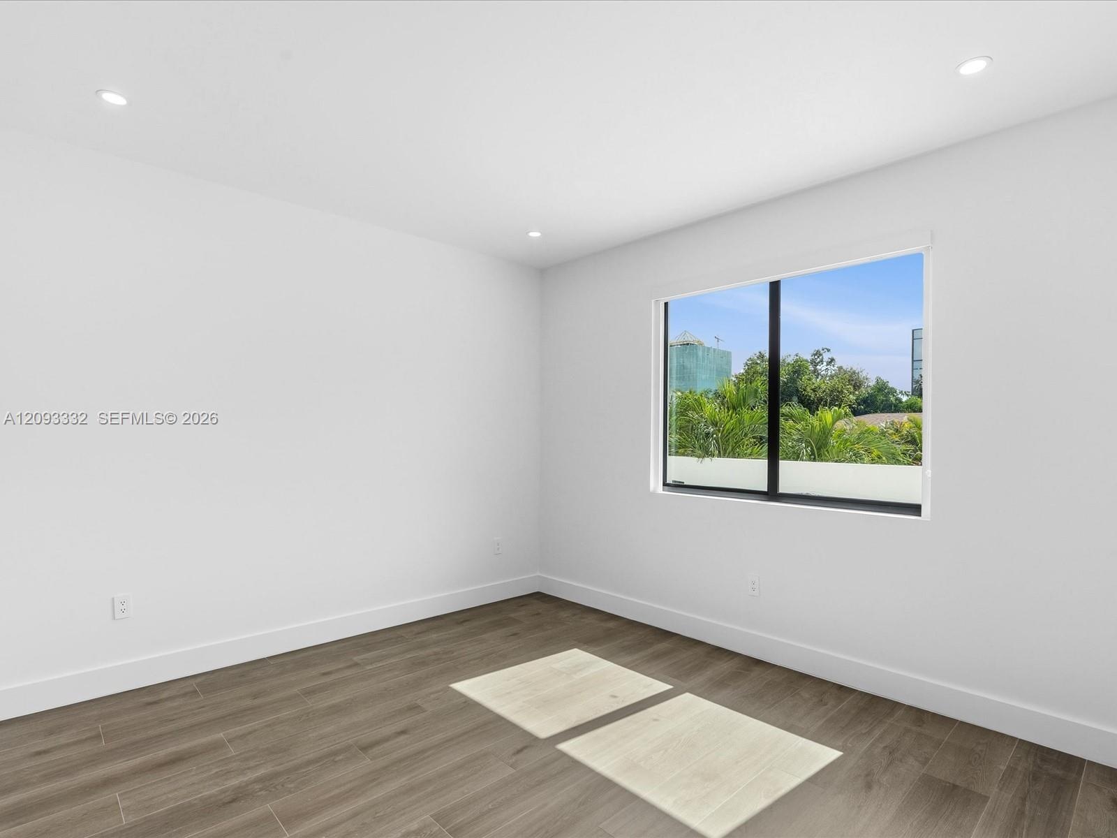 Neutral-toned wood-finish flooring, recessed lighting, and a single-pane window with black framing