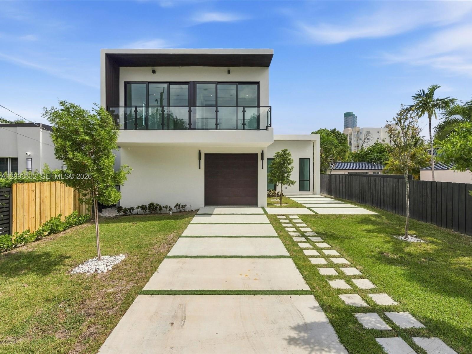 Modern two-story exterior featuring smooth stucco finish, expansive second-level glass balcony with metal railing, single-car garage, and geometric co