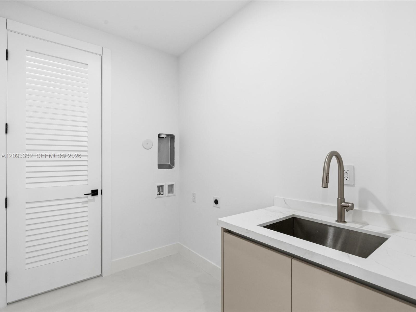 Utility area featuring a neutral-toned vanity with a stone-surface countertop, an integrated stainless steel drop-in sink, a high-arc faucet, and a wh