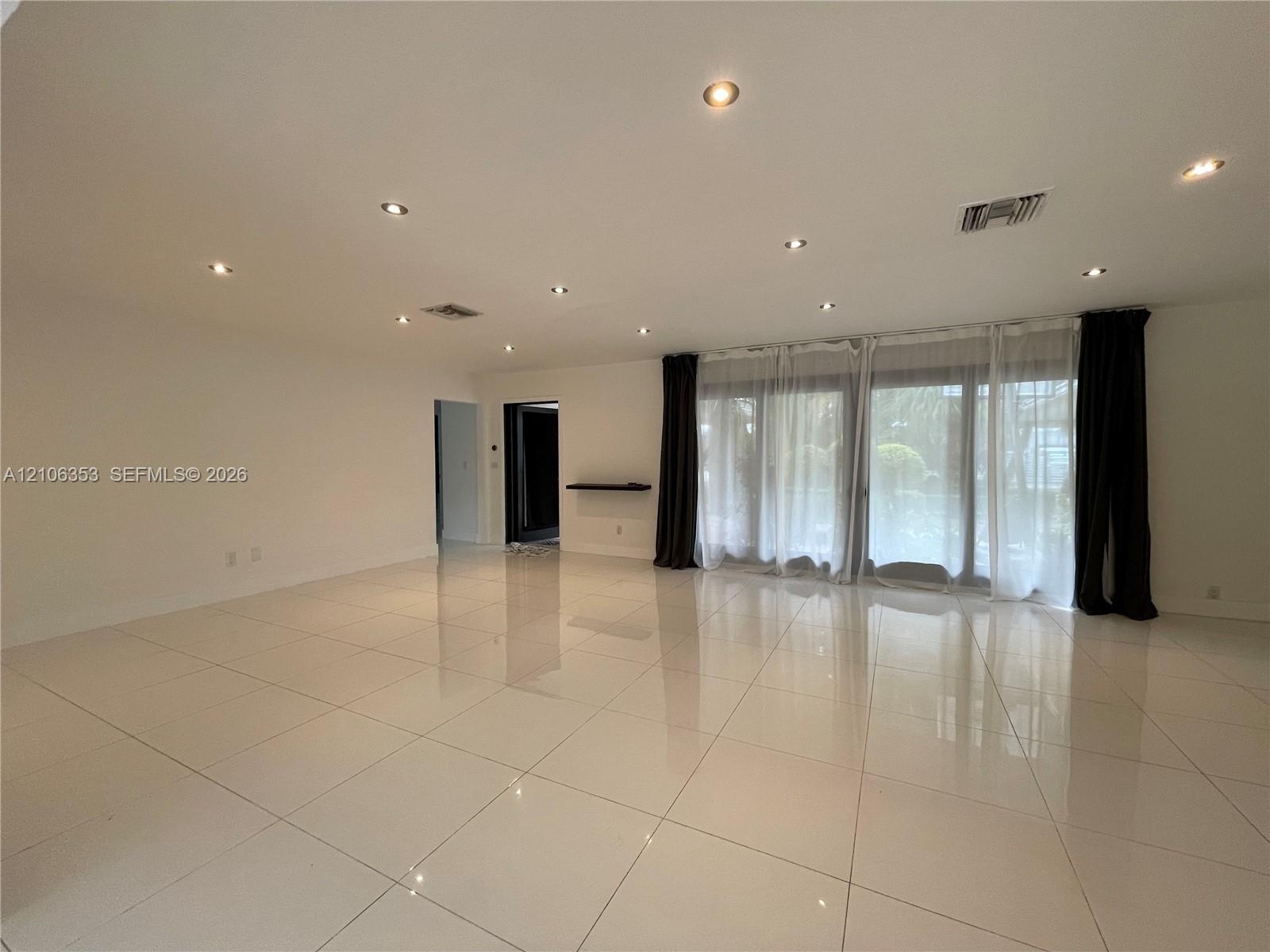 Polished tile flooring, recessed ceiling lighting, and expansive floor-to-ceiling glass sliding doors