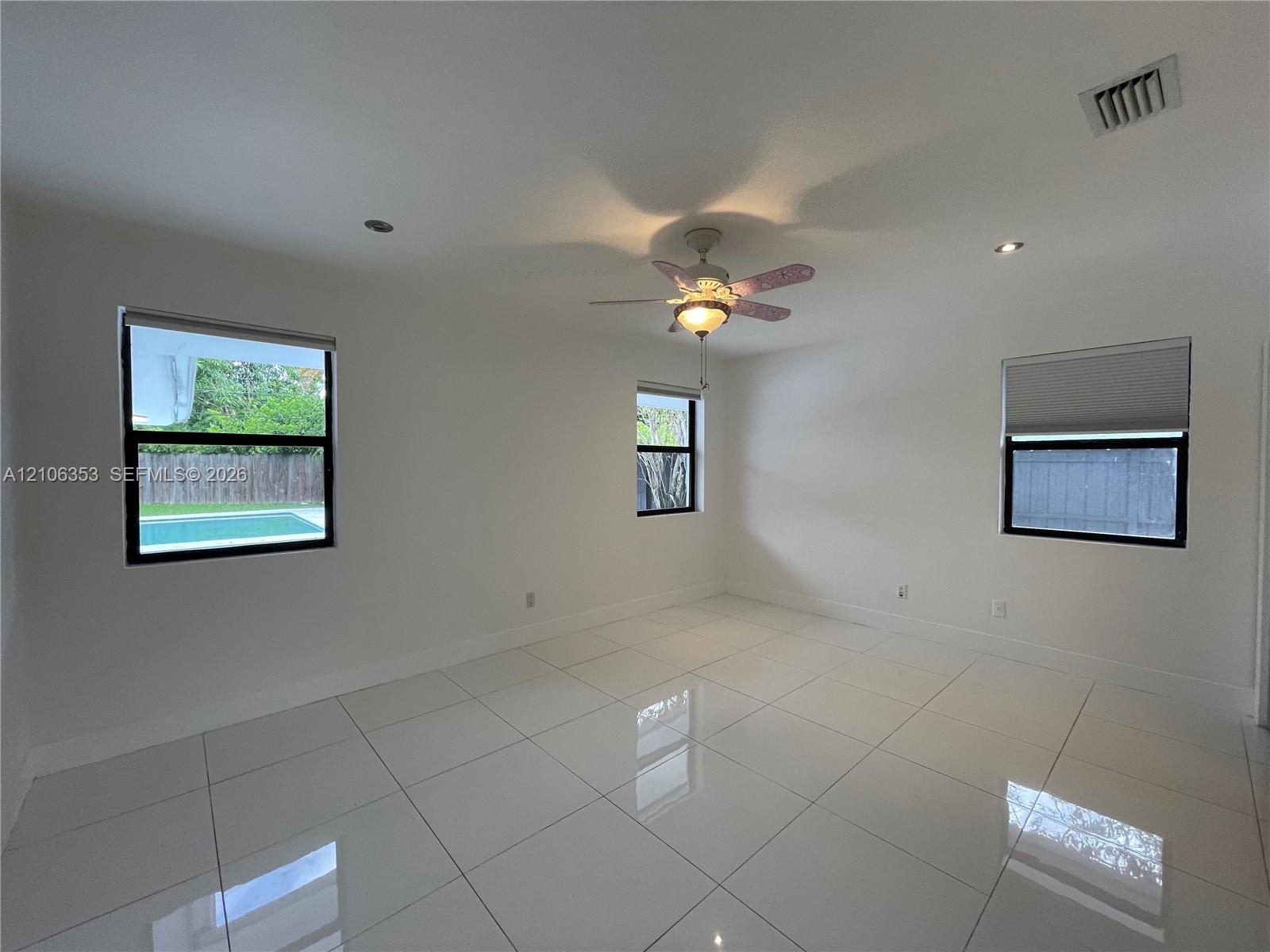 Polished large-format tile flooring, recessed lighting, ceiling fan with integrated lighting, and multiple windows with roller shades