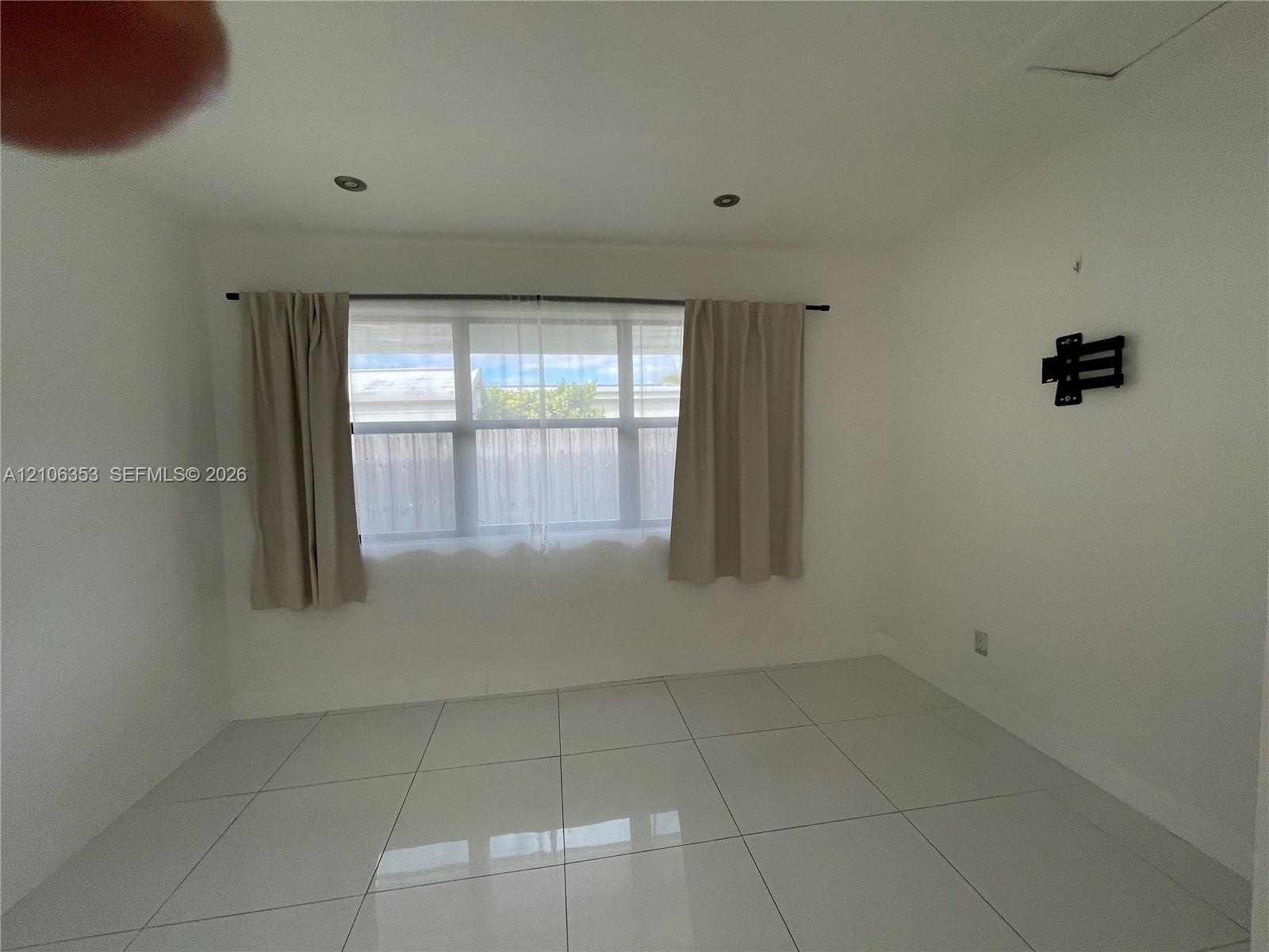 Large-format tile flooring, recessed ceiling lighting, and a multi-pane horizontal window featuring a metal curtain rod