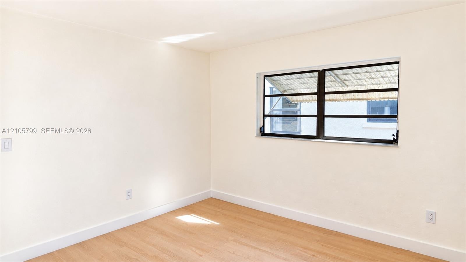 Neutral-toned interior featuring wood-finish flooring and a multi-pane awning window with dark frames