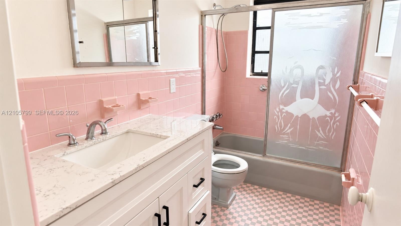 Bathroom featuring a white vanity with a composite countertop, ceramic wall tiling, a bathtub with an etched-glass sliding door, and checkered floorin