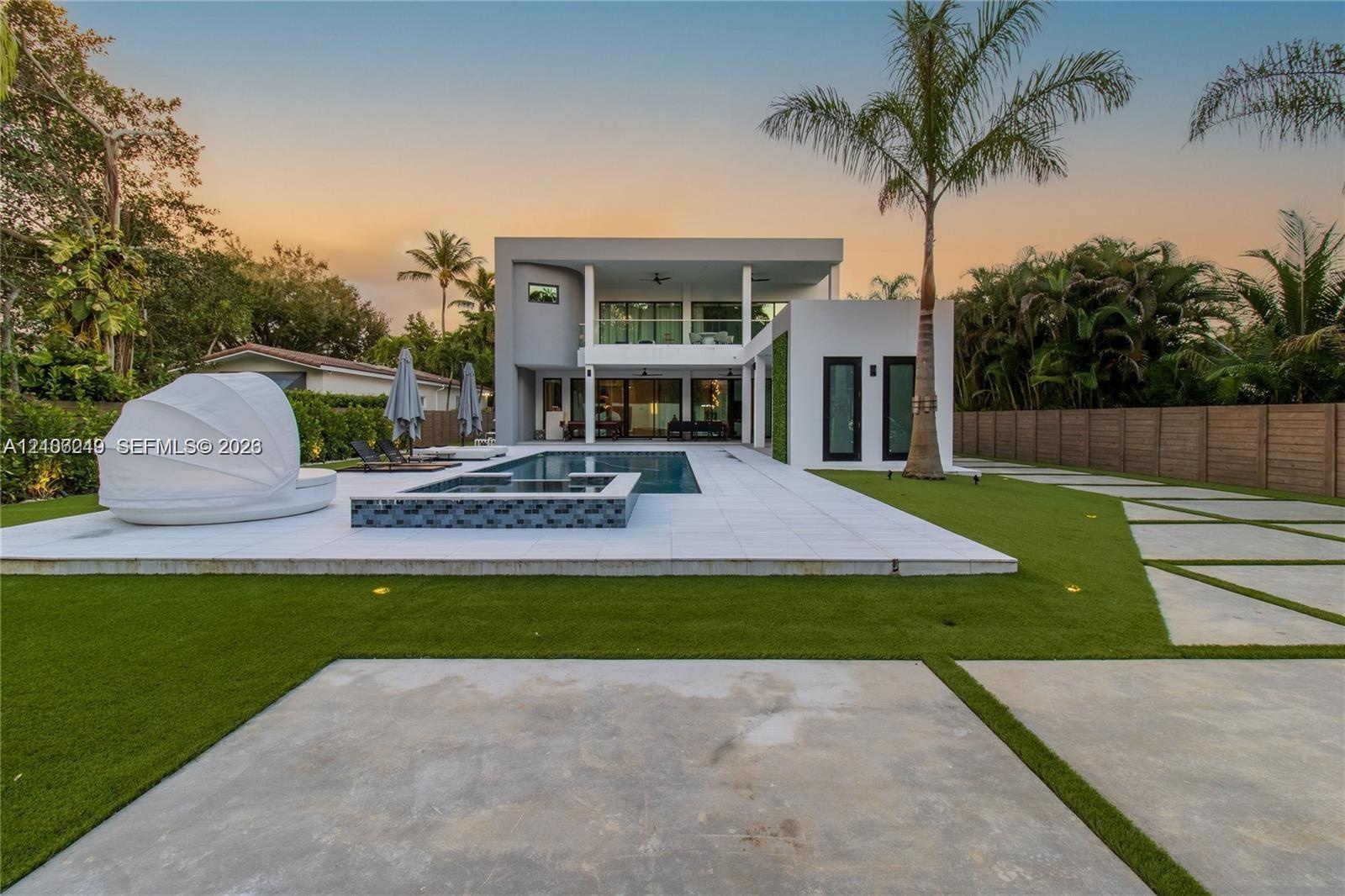 Modern exterior featuring a two-story flat roofline, integrated swimming pool with tiled spa, large-format porcelain patio pavers, and minimalist conc