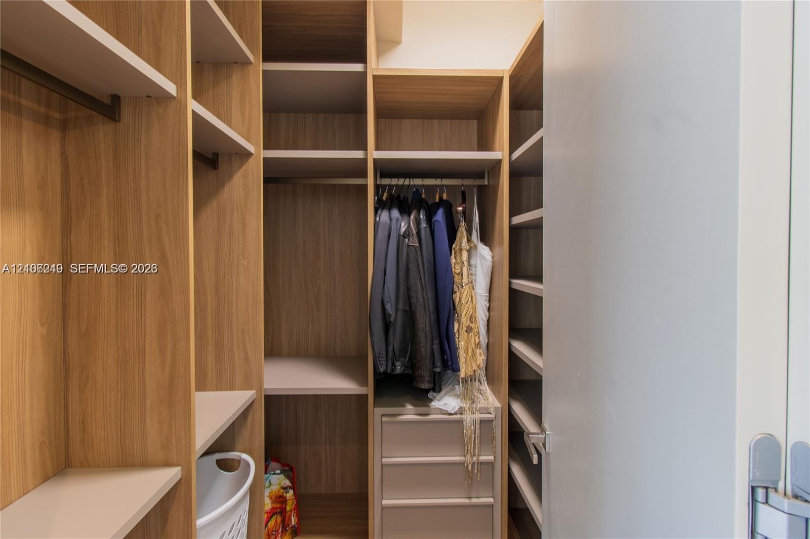 Custom reach-in closet featuring wood-finish cabinetry, built-in shelving, integrated garment rods, and a stack of three storage drawers