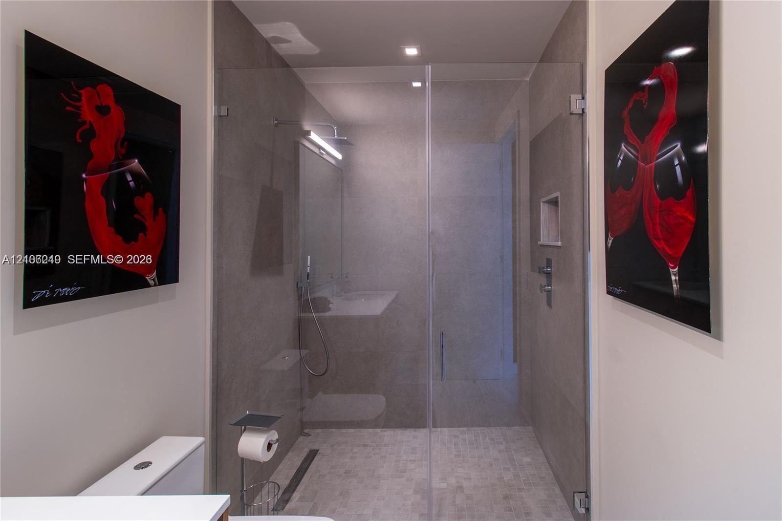 Walk-in shower featuring a frameless glass enclosure, neutral tile surround, built-in wall niche, and integrated linear drain