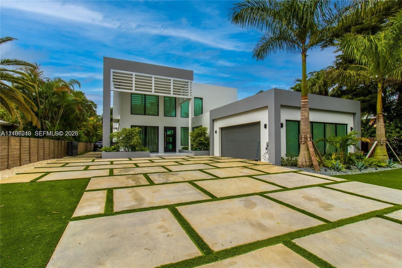 Contemporary multi-level exterior featuring clean geometric lines, large-format concrete paver driveway with turf accents, high-profile louvered archi