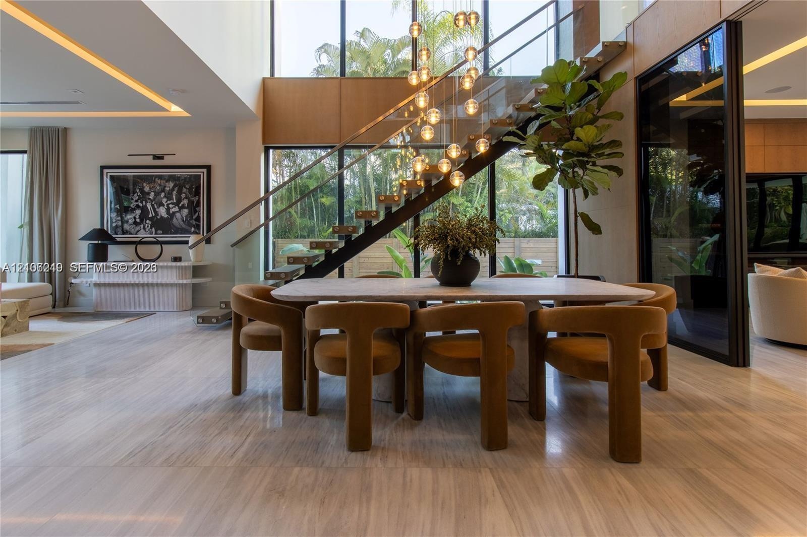 Double-height ceiling featuring floor-to-ceiling windows, open-riser staircase with glass balustrade, stone flooring, integrated recessed lighting, an