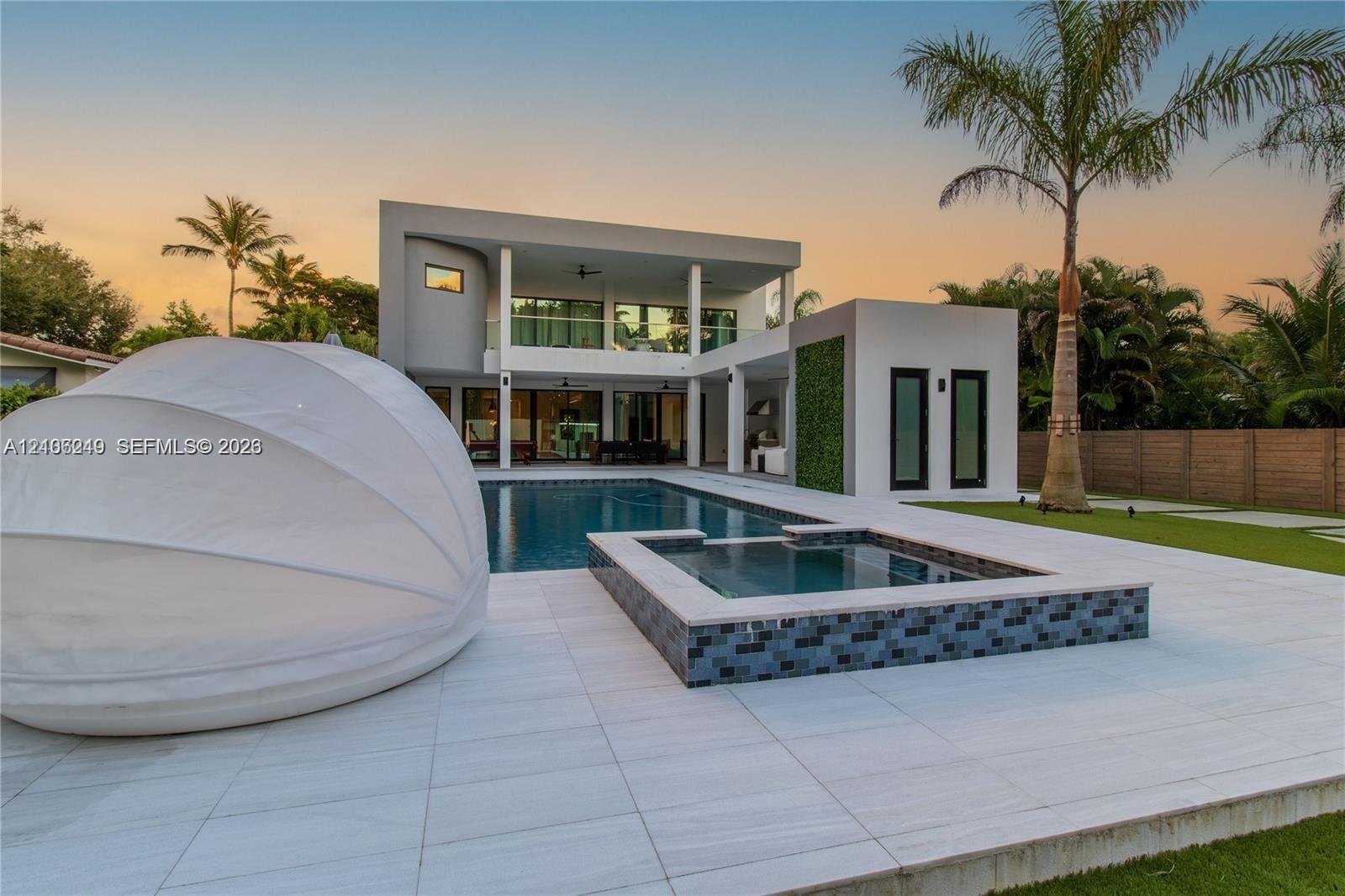 Contemporary exterior featuring a two-story structure, expansive pool, elevated spa with tile cladding, covered patio area, and vertical garden wall