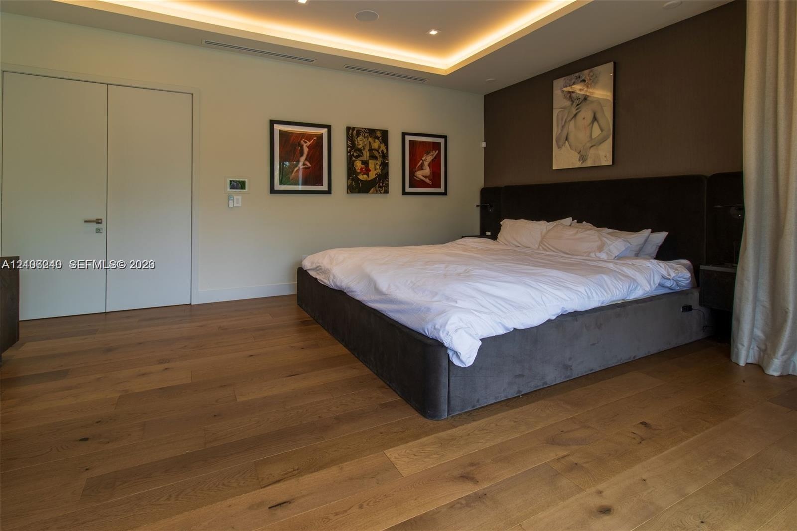 Tray ceiling with integrated recessed lighting, wood-finish flooring, and solid-core doors