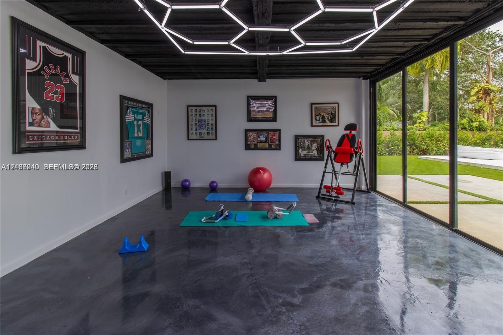 Polished concrete flooring, geometric LED ceiling lighting, and expansive sliding glass doors opening to a paved patio area