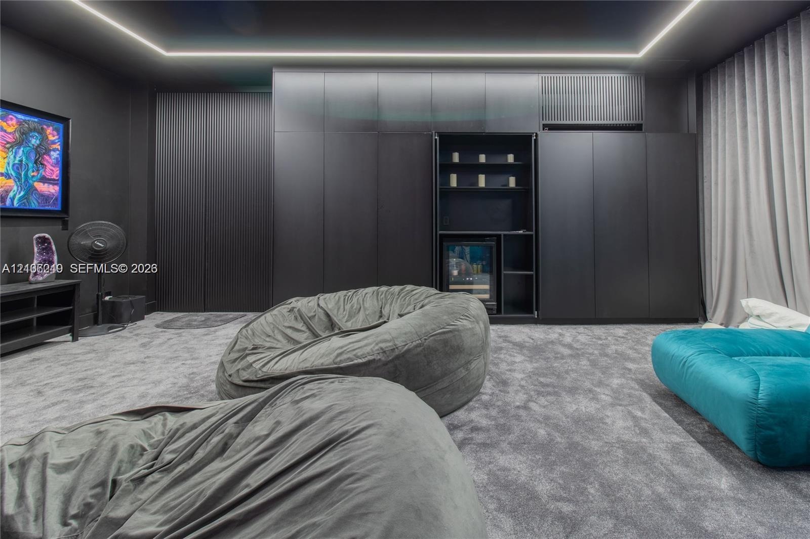 Floor-to-ceiling matte black cabinetry, integrated shelving unit with a built-in beverage refrigerator, cove ceiling lighting, and wall-to-wall carpet