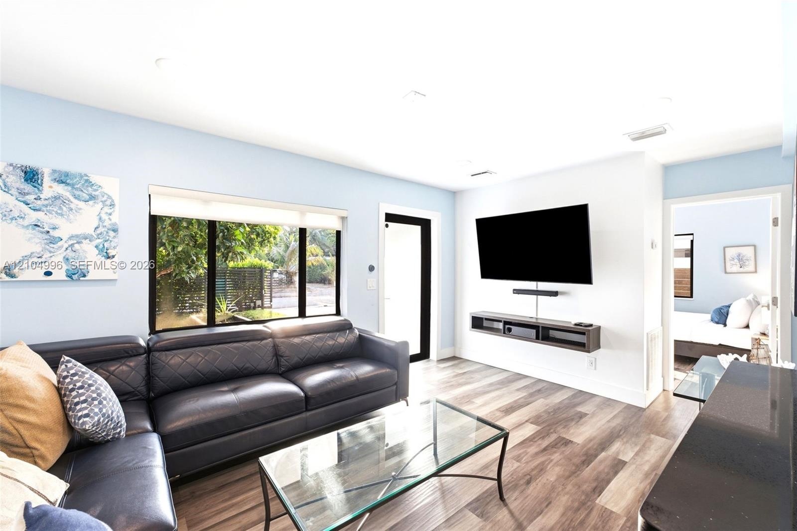Living area featuring wood-finish flooring, recessed lighting, a large picture window, and a built-in floating media console