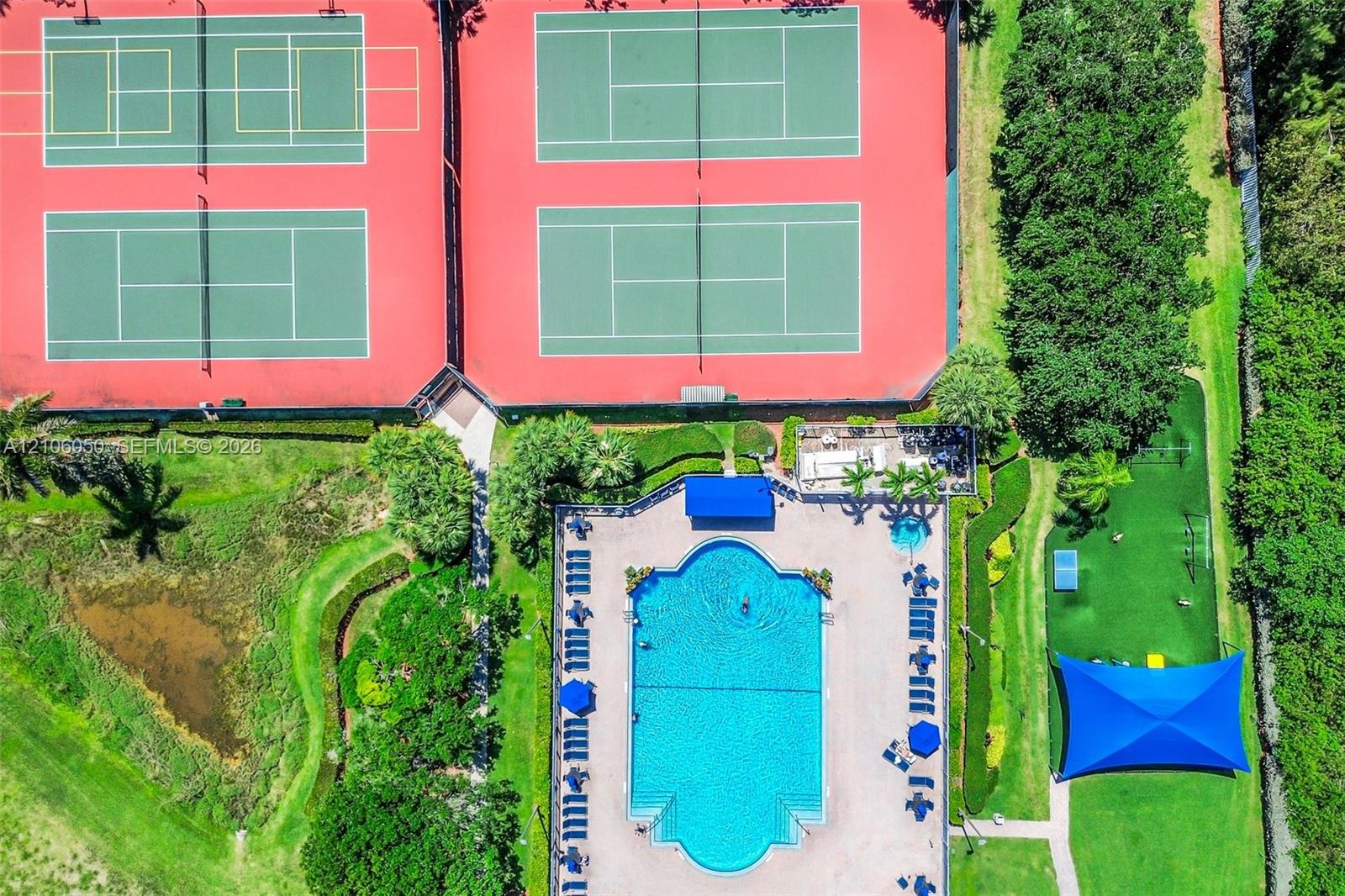 Recreational complex featuring four tennis courts, a swimming pool, a separate spa, and a shaded outdoor area with turf