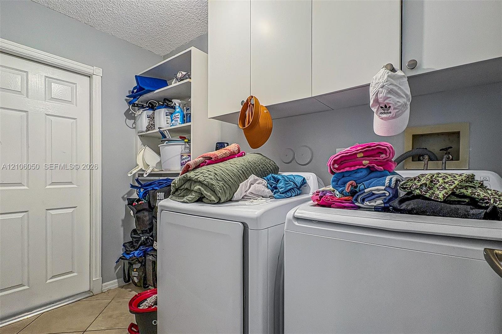 Laundry room featuring white wall-mounted cabinetry, open shelving, and tile flooring