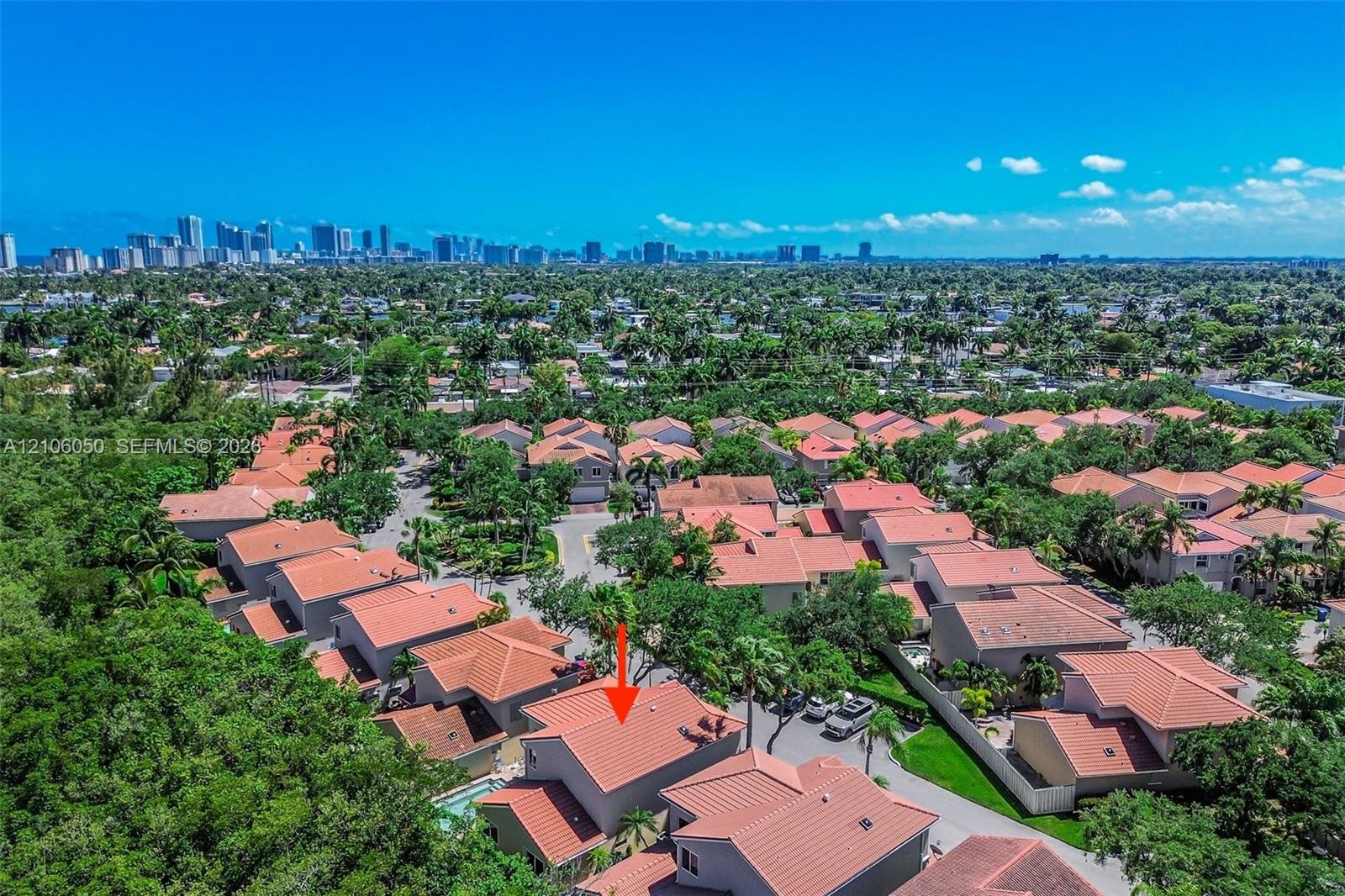 Aerial perspective of a multi-story residence featuring a terracotta tile roof and an in-ground swimming pool, situated within a suburban residential 