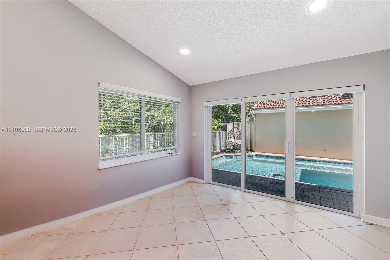 Interior space featuring vaulted ceilings, recessed lighting, tile flooring, and oversized sliding glass doors