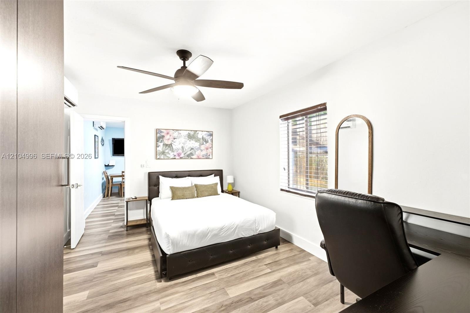 Wood-finish flooring, ceiling fan with integrated light, horizontal window blinds, and interior doors