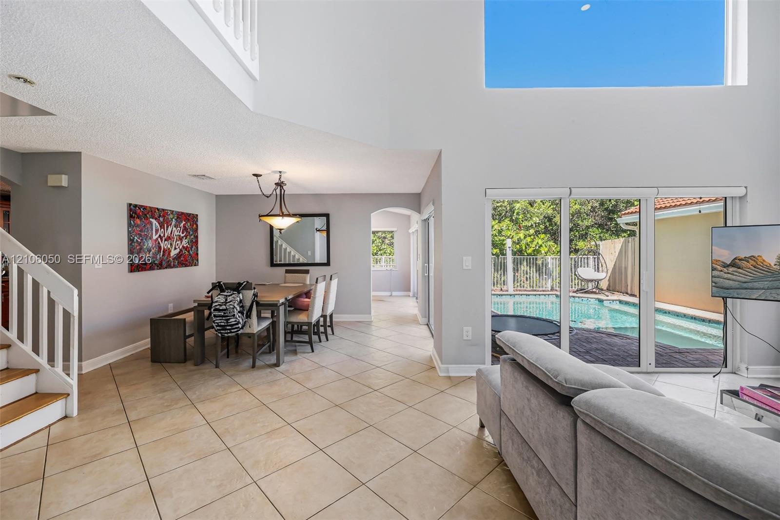 Vaulted ceilings, porcelain tile flooring, sliding glass doors, and a wood-railing staircase