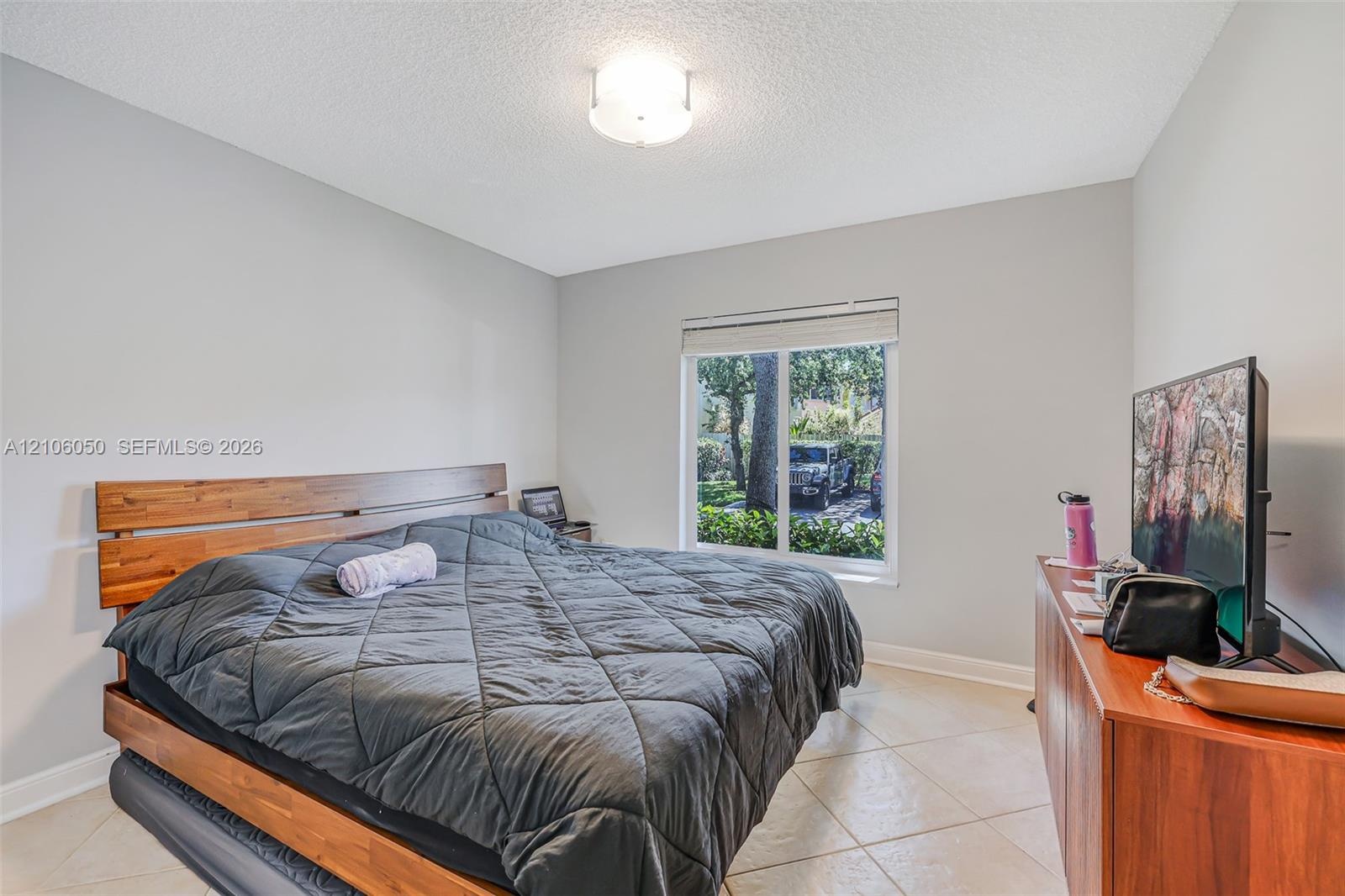 Neutral-toned walls, tile flooring, flush-mount ceiling lighting, and a window with a horizontal blind