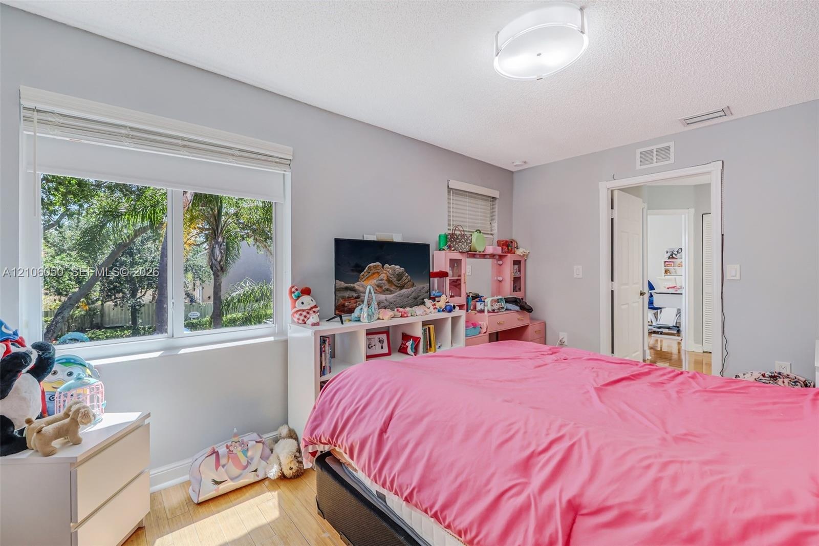 Bedroom featuring wood-finish flooring, dual-pane windows, and a semi-flush mount light fixture