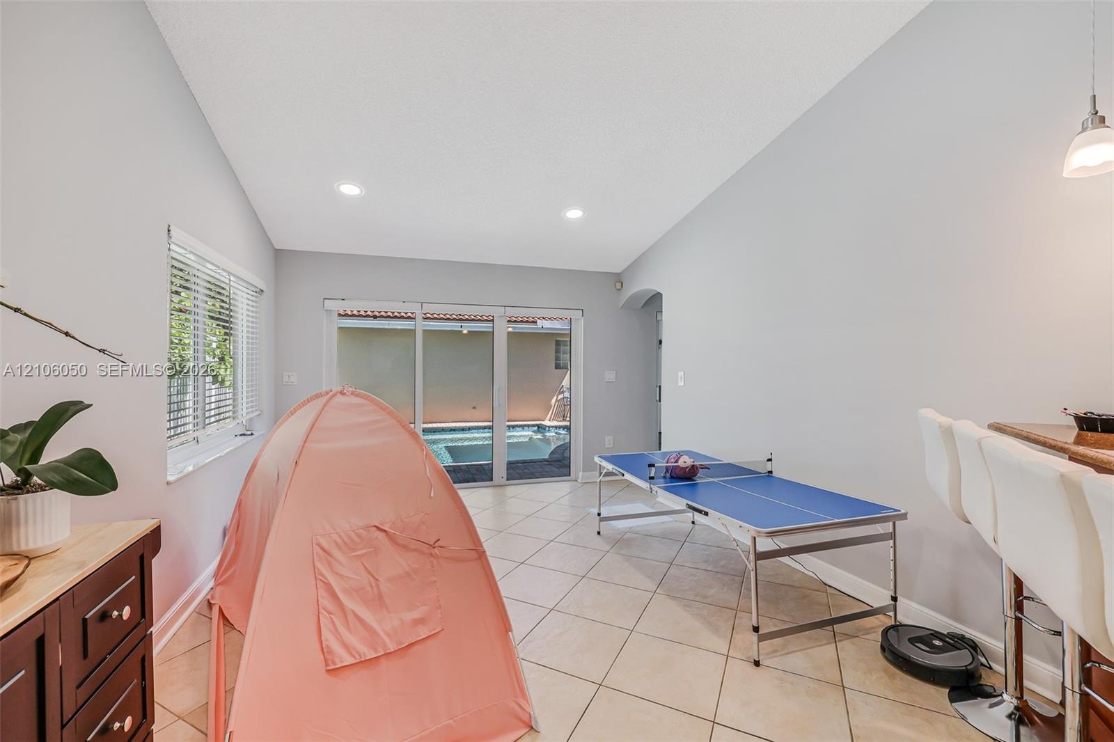 Vaulted ceilings with recessed lighting, tile flooring, sliding glass doors, and a built-in wet bar with cabinetry