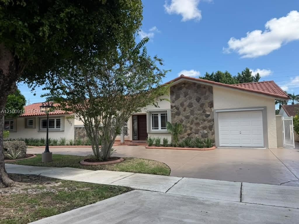 Covered rear patio featuring tile flooring, a built-in outdoor counter, and a expansive lawn